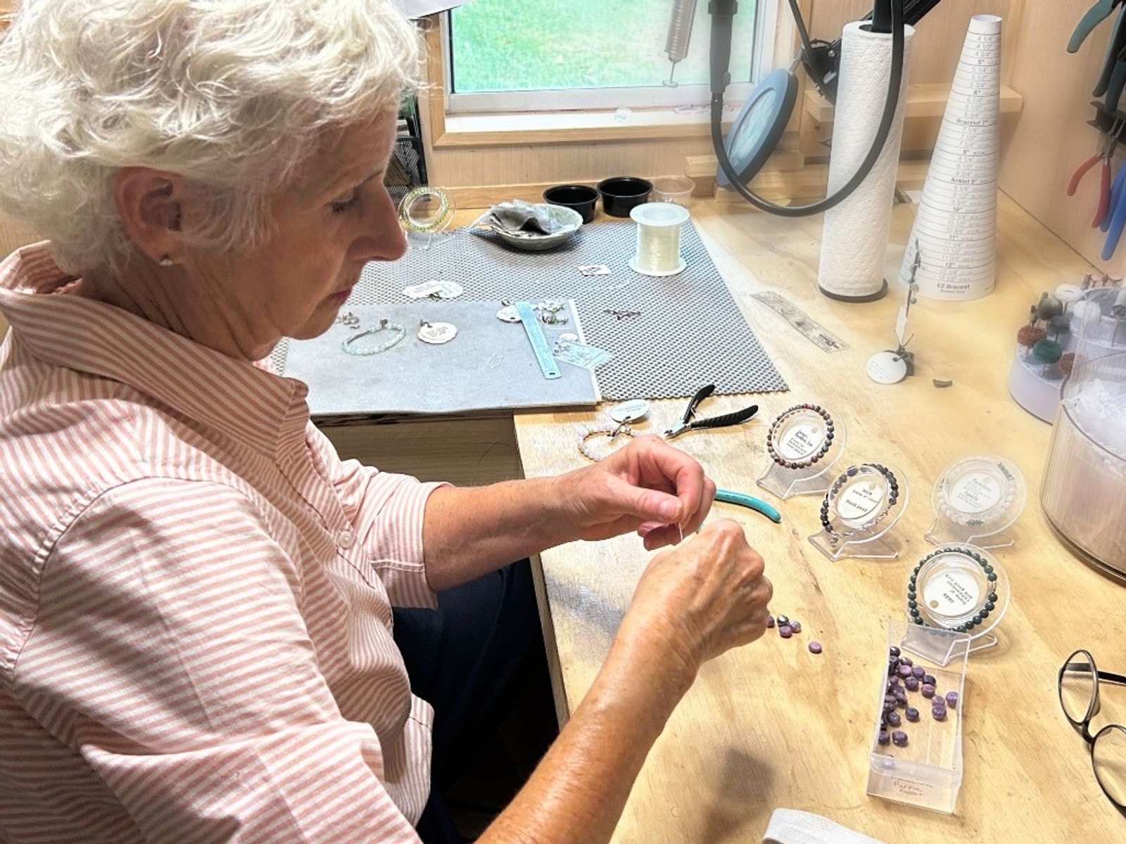 Renie stringing gemstone beads at her workbench
